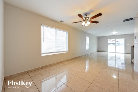 an empty living room with a ceiling fan and tiled floors