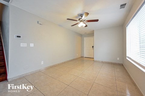 an empty living room with a ceiling fan and a tiled floor