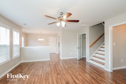 an empty living room with a ceiling fan and stairs