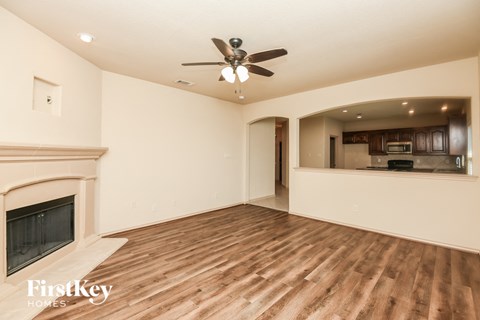 an empty living room with a fireplace and a ceiling fan