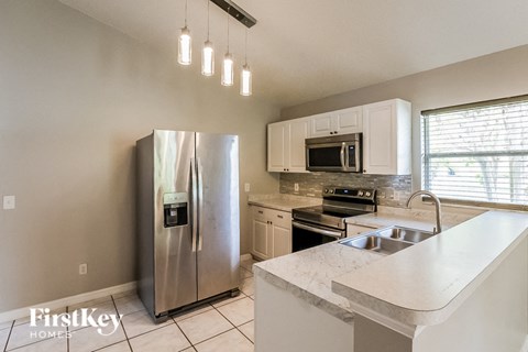 A kitchen with a stainless steel refrigerator, microwave, and oven.