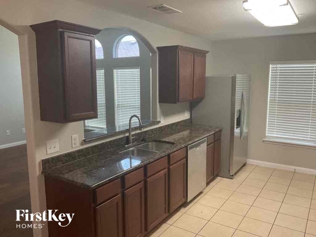 A kitchen with brown cabinets and a black countertop.