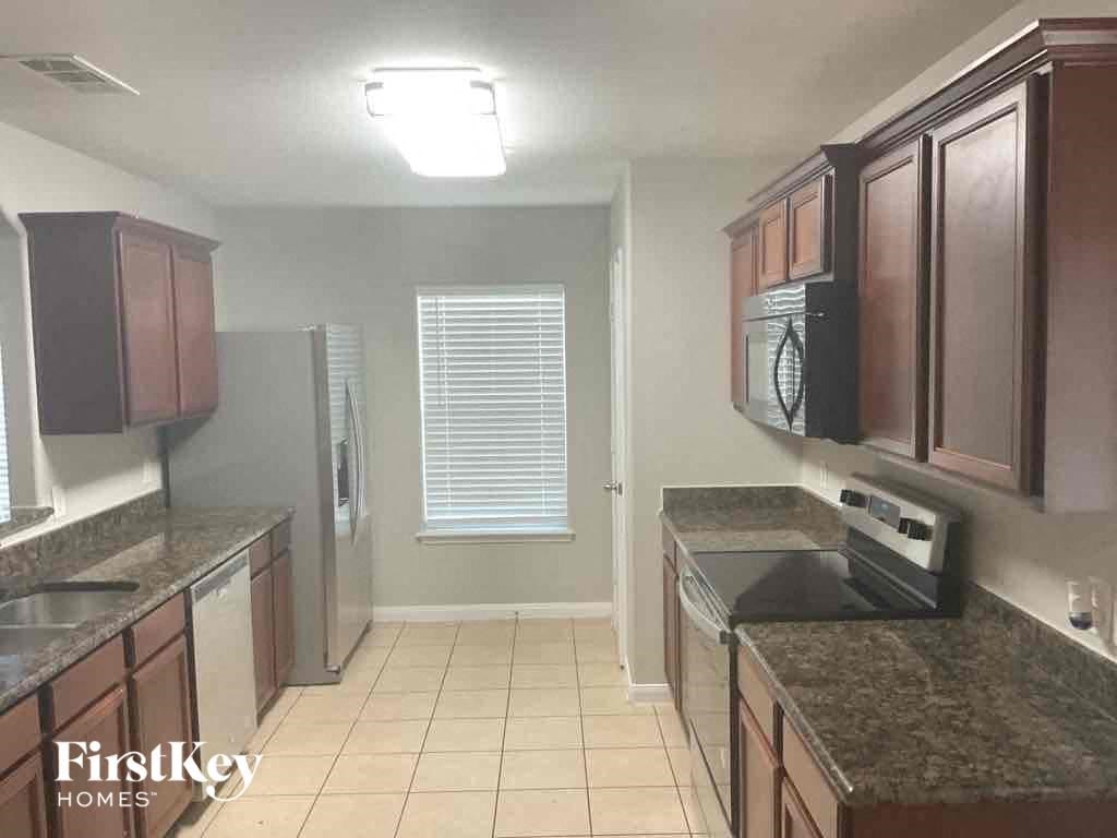 A kitchen with brown cabinets and a black stove top oven.