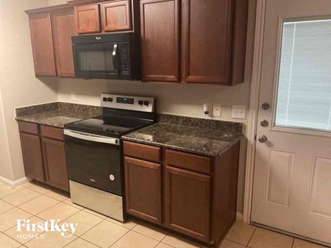 A kitchen with brown cabinets and a black microwave.
