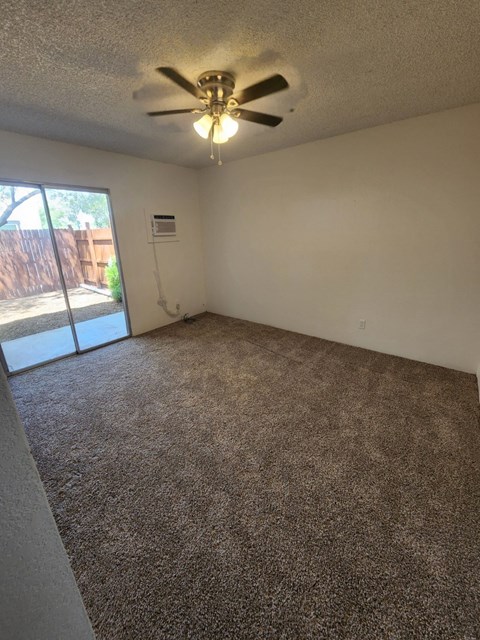 an empty living room with a ceiling fan and a window