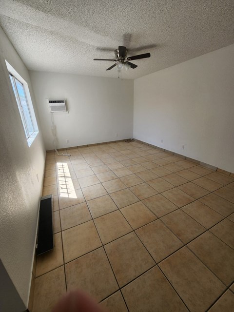 an empty living room with a ceiling fan and tiled floors