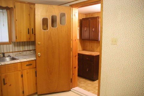 a kitchen with wooden cabinets and a sink and an open door