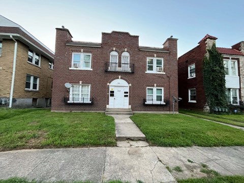 the front of a brick house with a white door and a lawn