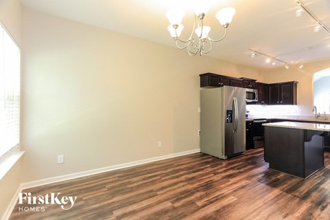 A kitchen with a refrigerator and a dining table.