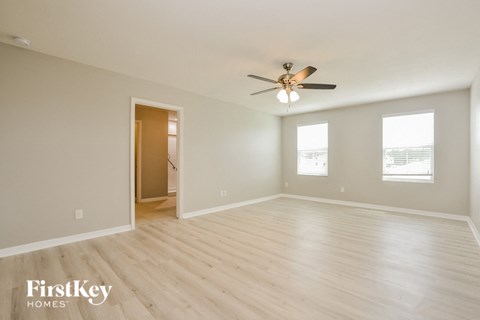 A spacious room with a ceiling fan and wooden flooring.