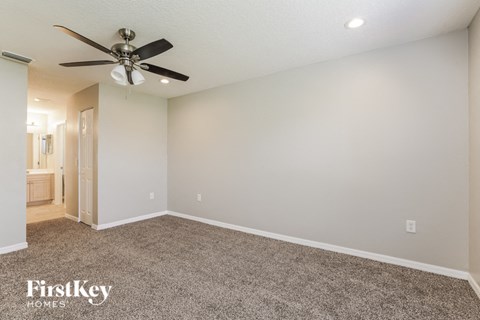 the spacious living room with ceiling fan and carpet