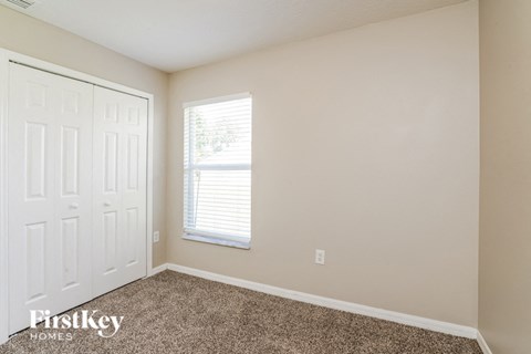 a bedroom with carpet and a white door and window