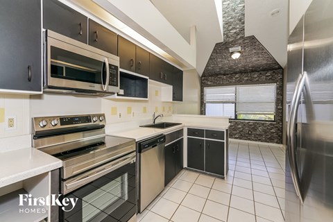 A kitchen with stainless steel appliances and black cabinets.