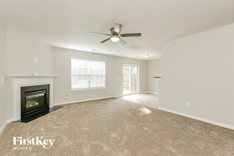 A spacious room with a fireplace and a ceiling fan.