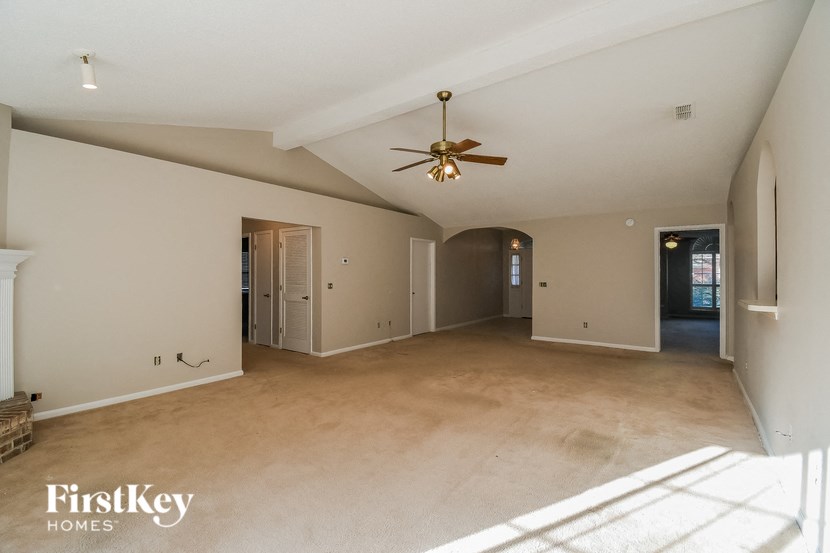 a large empty living room with a ceiling fan