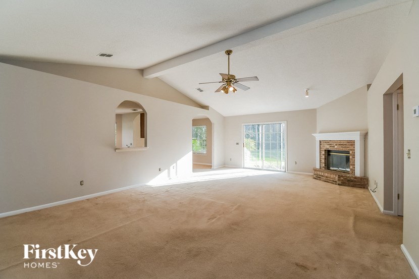 a empty living room with a ceiling fan and a fireplace