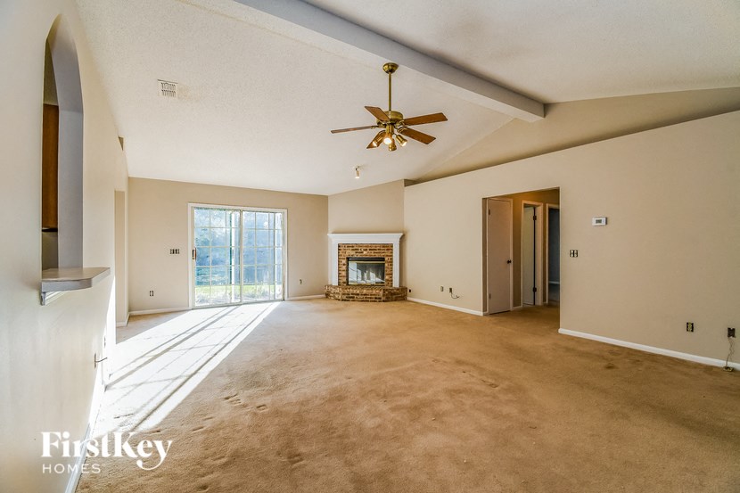 a empty living room with a ceiling fan and a fireplace