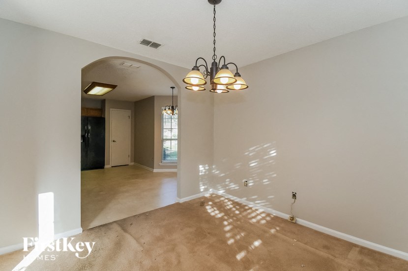 a empty living room and dining room with a chandelier