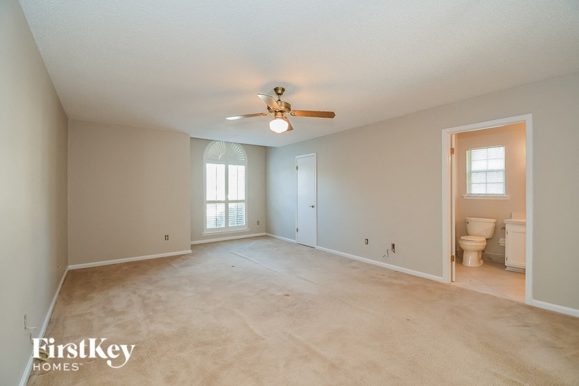 an empty living room with a ceiling fan and a toilet