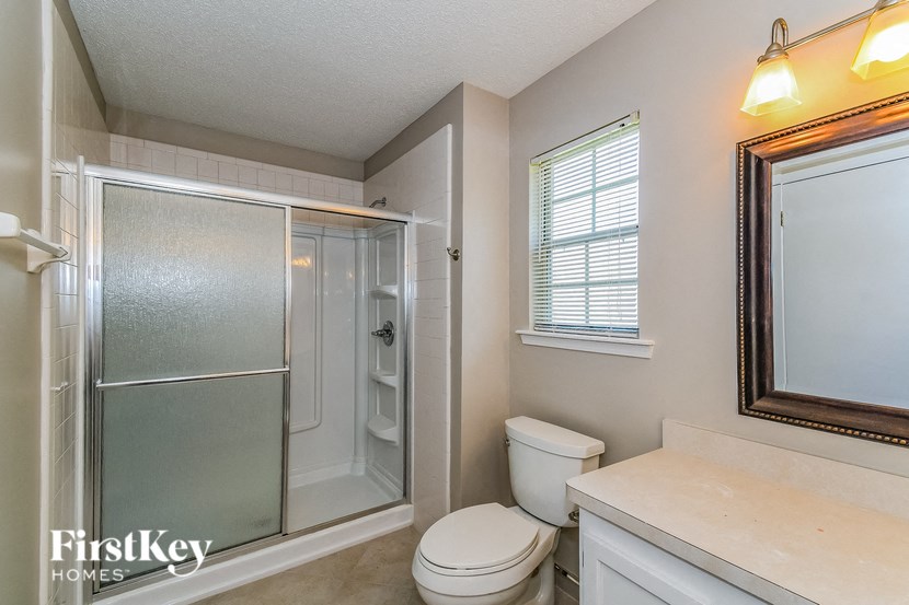 a bathroom with a shower toilet and a mirror