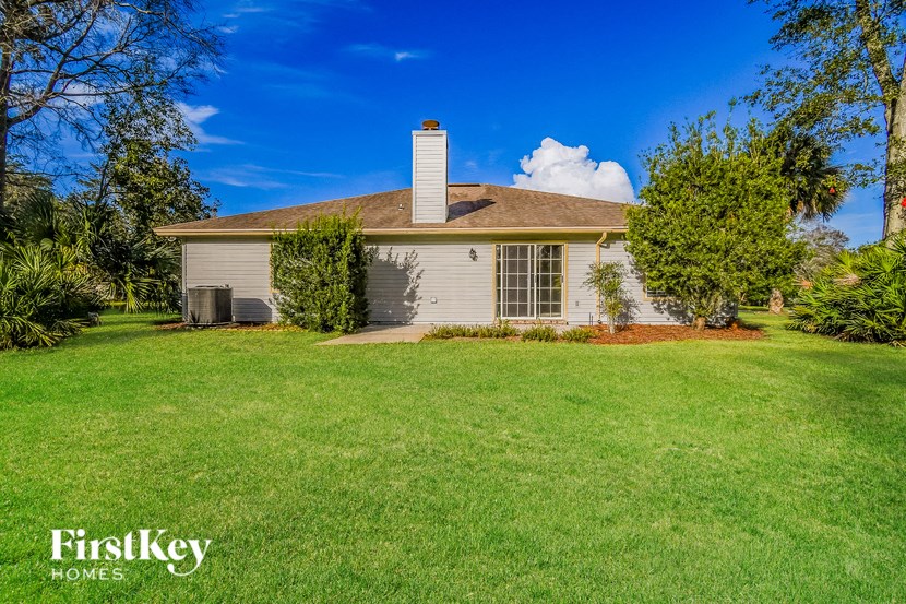 a small white house with a lawn and trees