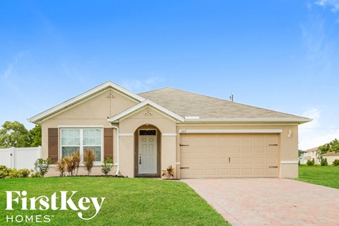 a beige house with a driveway and grass