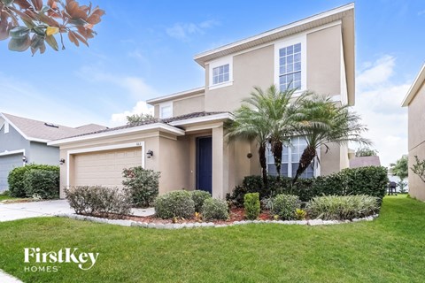 A house with a well-maintained lawn and a palm tree in front.