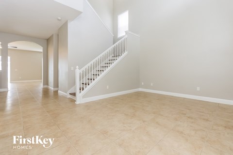 A spacious room with a staircase and a large window.