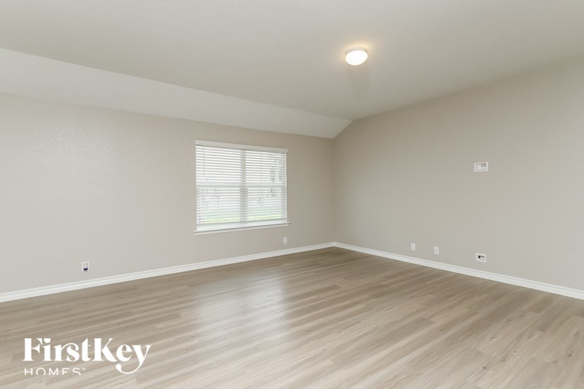 the spacious living room with wood floors and white walls