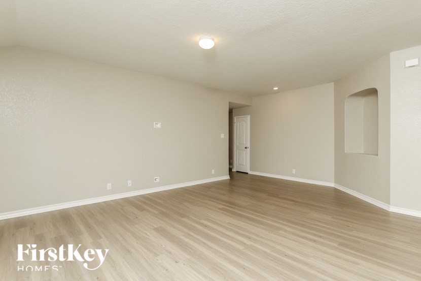 a spacious living room with wood flooring and white walls