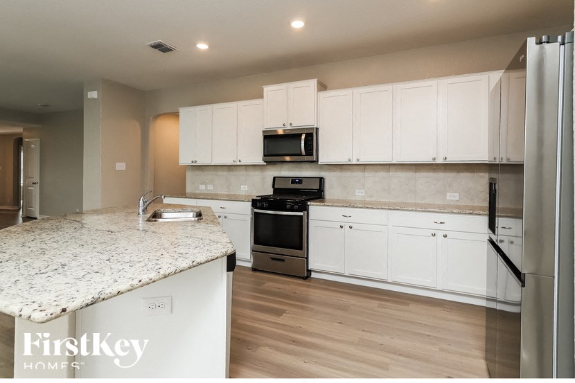 a kitchen with white cabinets and a marble counter top