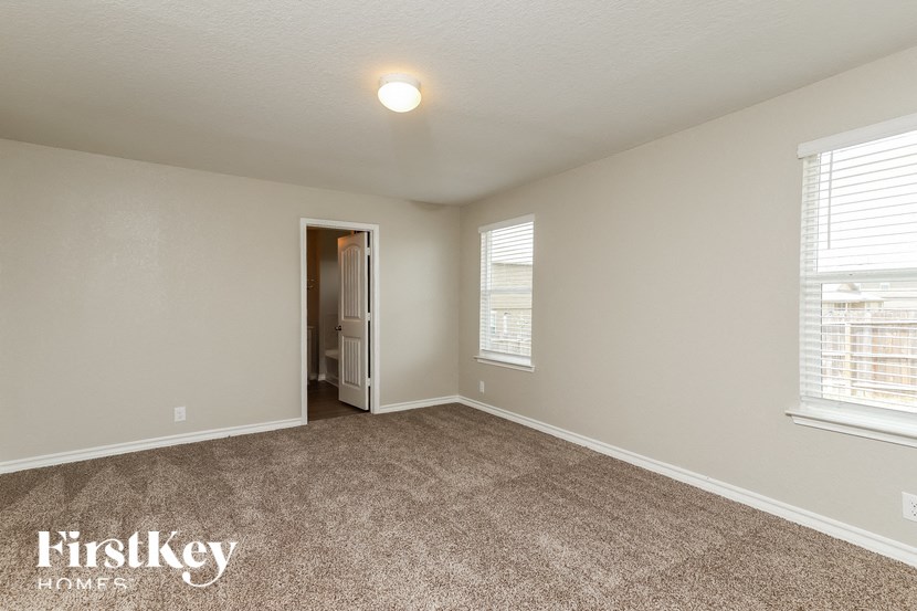the spacious living room with carpeting and a door to the bathroom