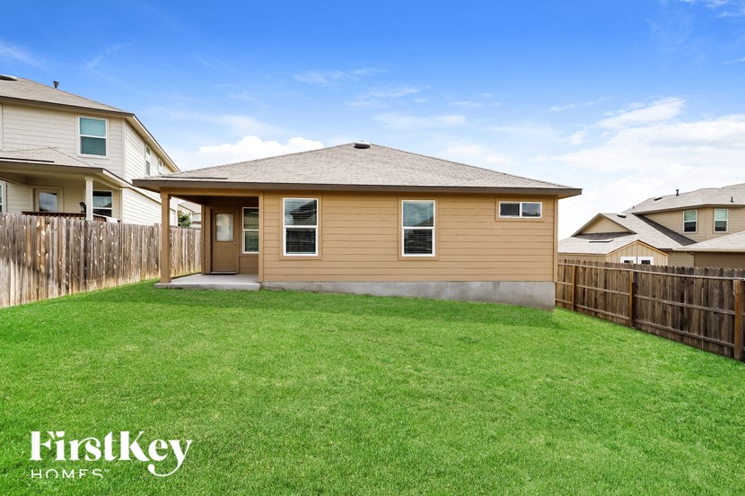 a backyard with a house and a grass lawn