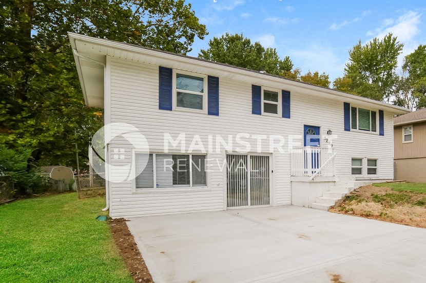 a white house with blue shutters and a driveway