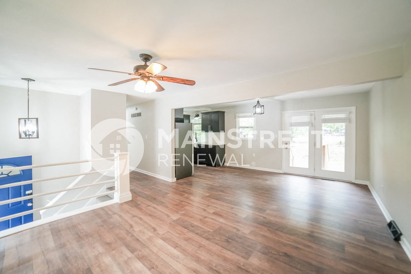 a renovated living room with a staircase and a ceiling fan