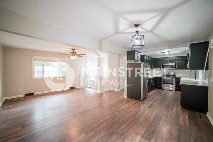 a renovated living room and kitchen with a hard wood floor