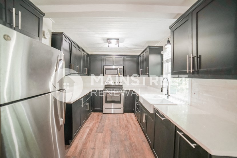 a renovated kitchen with black cabinets and stainless steel appliances