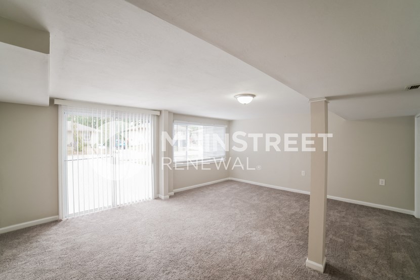 a living room with carpet and a door to a balcony