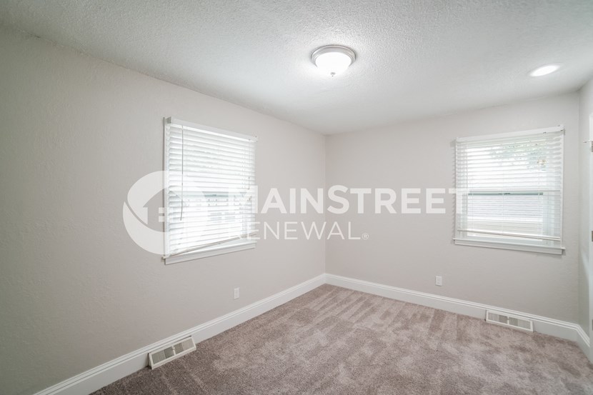 a bedroom with carpet and two windows