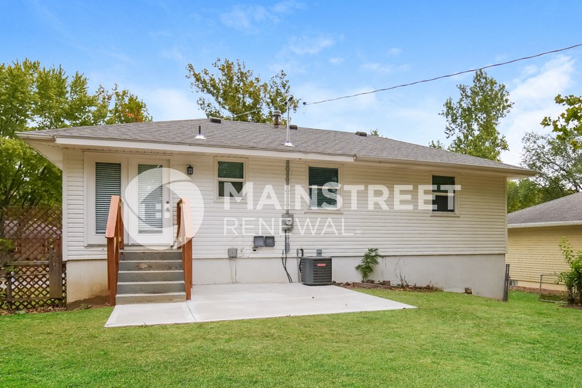 a small white house with a porch and a lawn