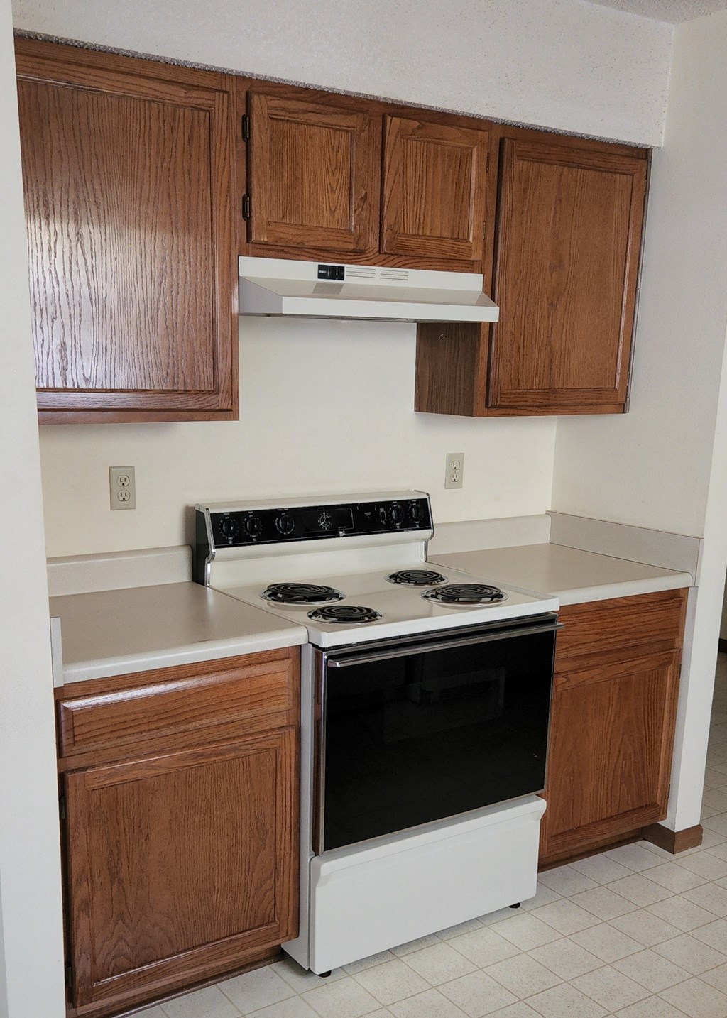 an empty kitchen with wooden cabinets and a stove top oven