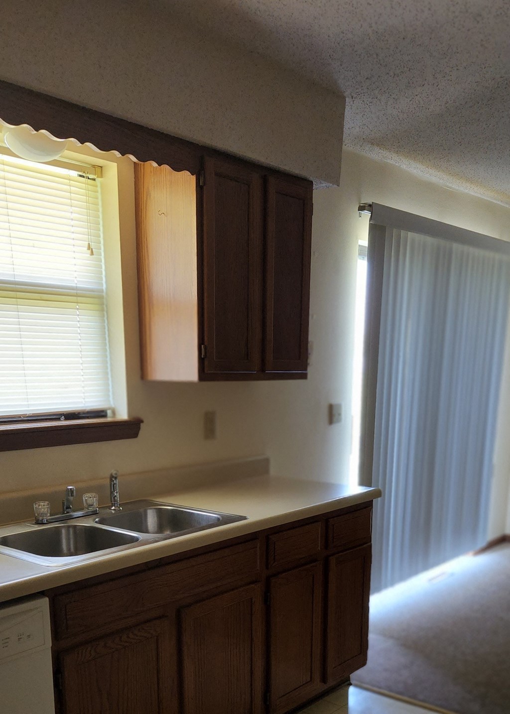 a kitchen with a sink and a window and wooden cabinets
