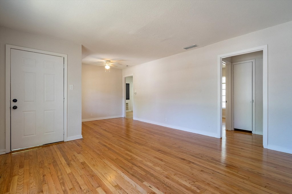 the living room and dining room of an empty house with wood flooring