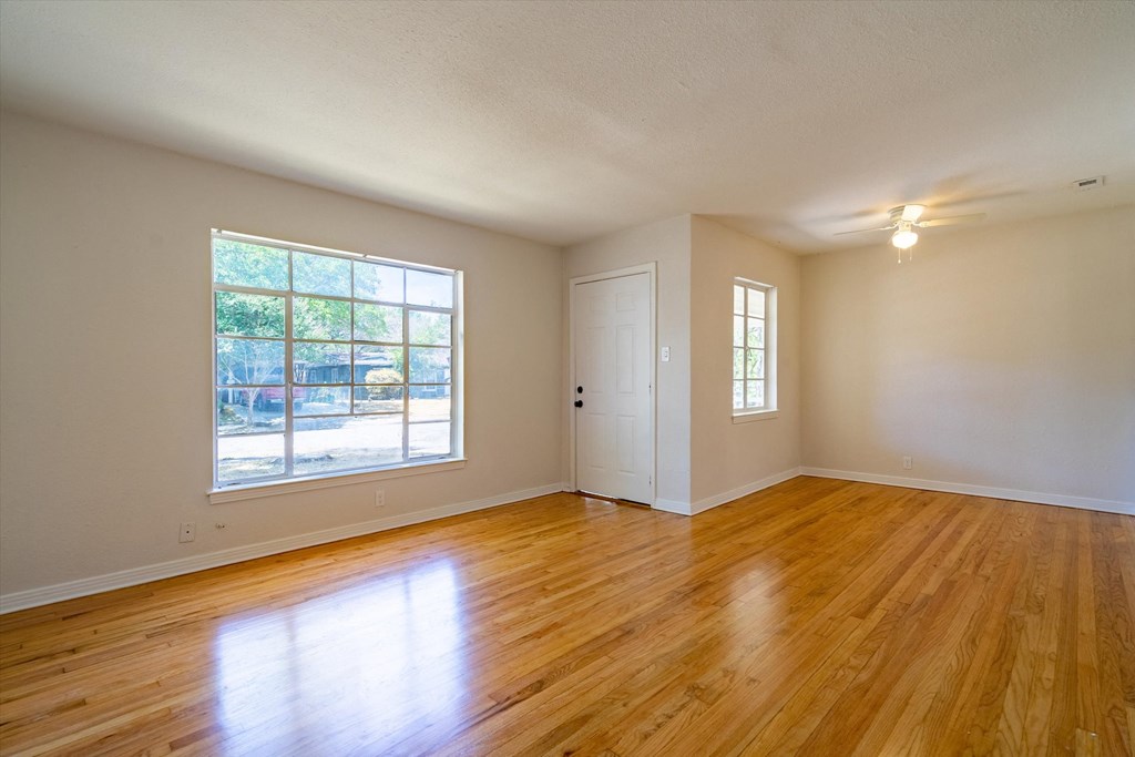 an empty living room with wood floors and a large window