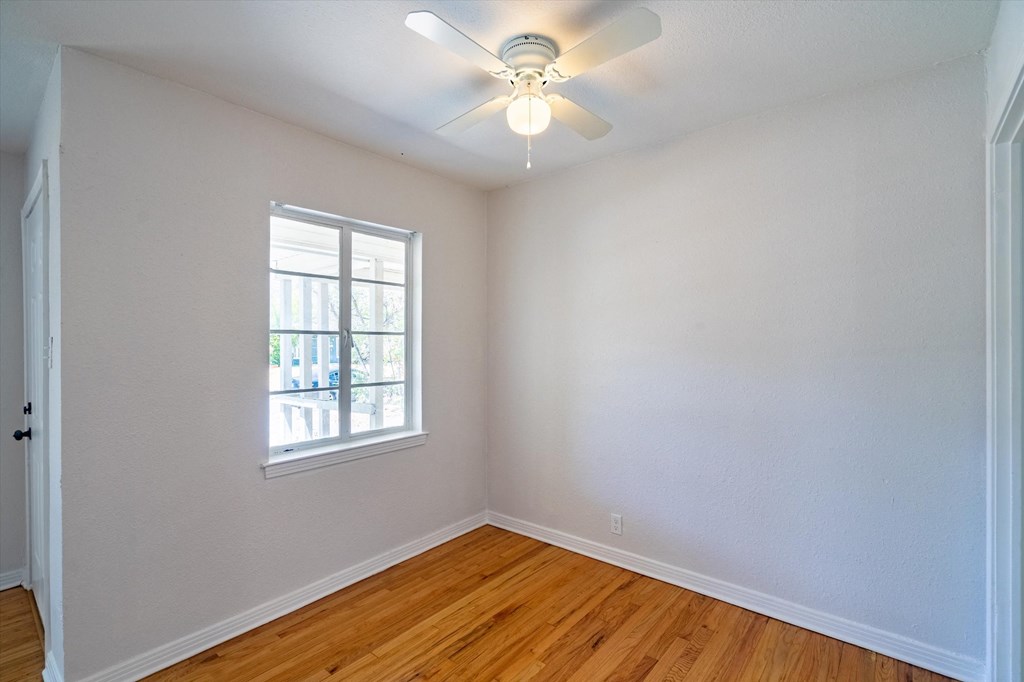 an empty room with a ceiling fan and a window