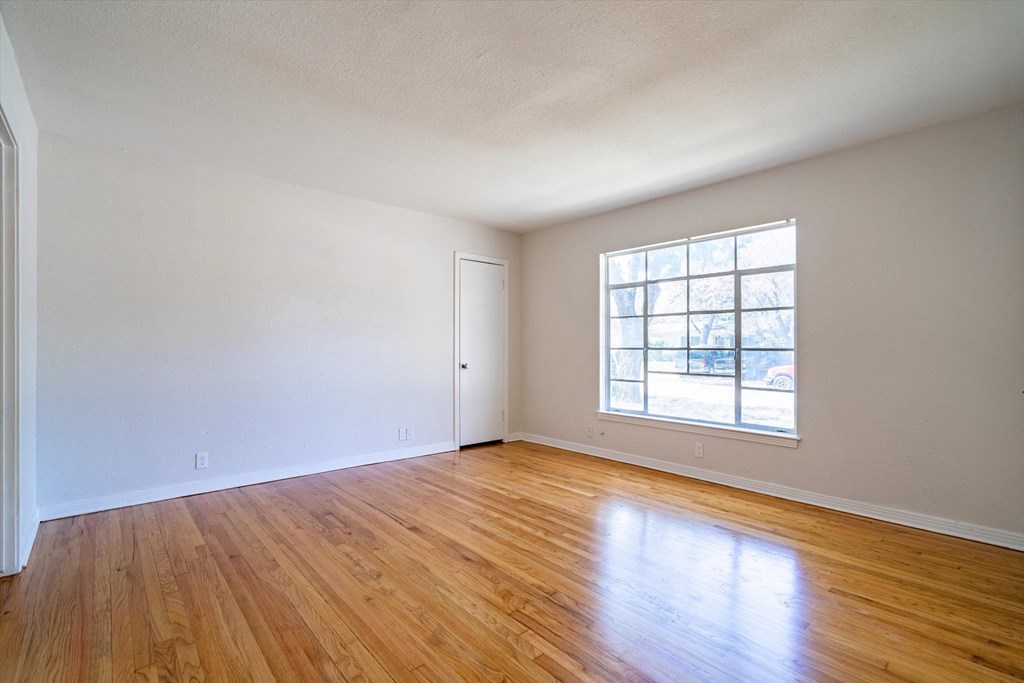 an empty living room with wood floors and a window