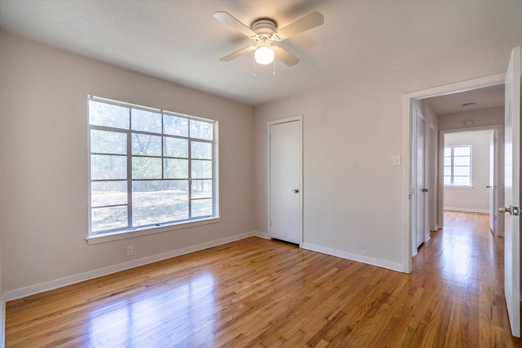 an empty living room with a ceiling fan and a large window