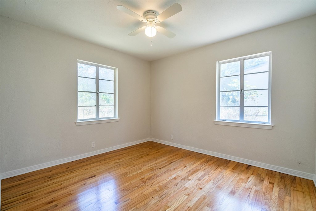 an empty living room with wood floors and a ceiling fan