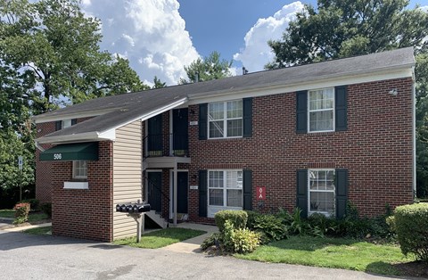 a red brick house with green shutters and a driveway