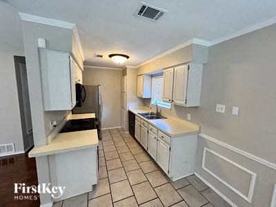 A kitchen with white cabinets and a tile floor.